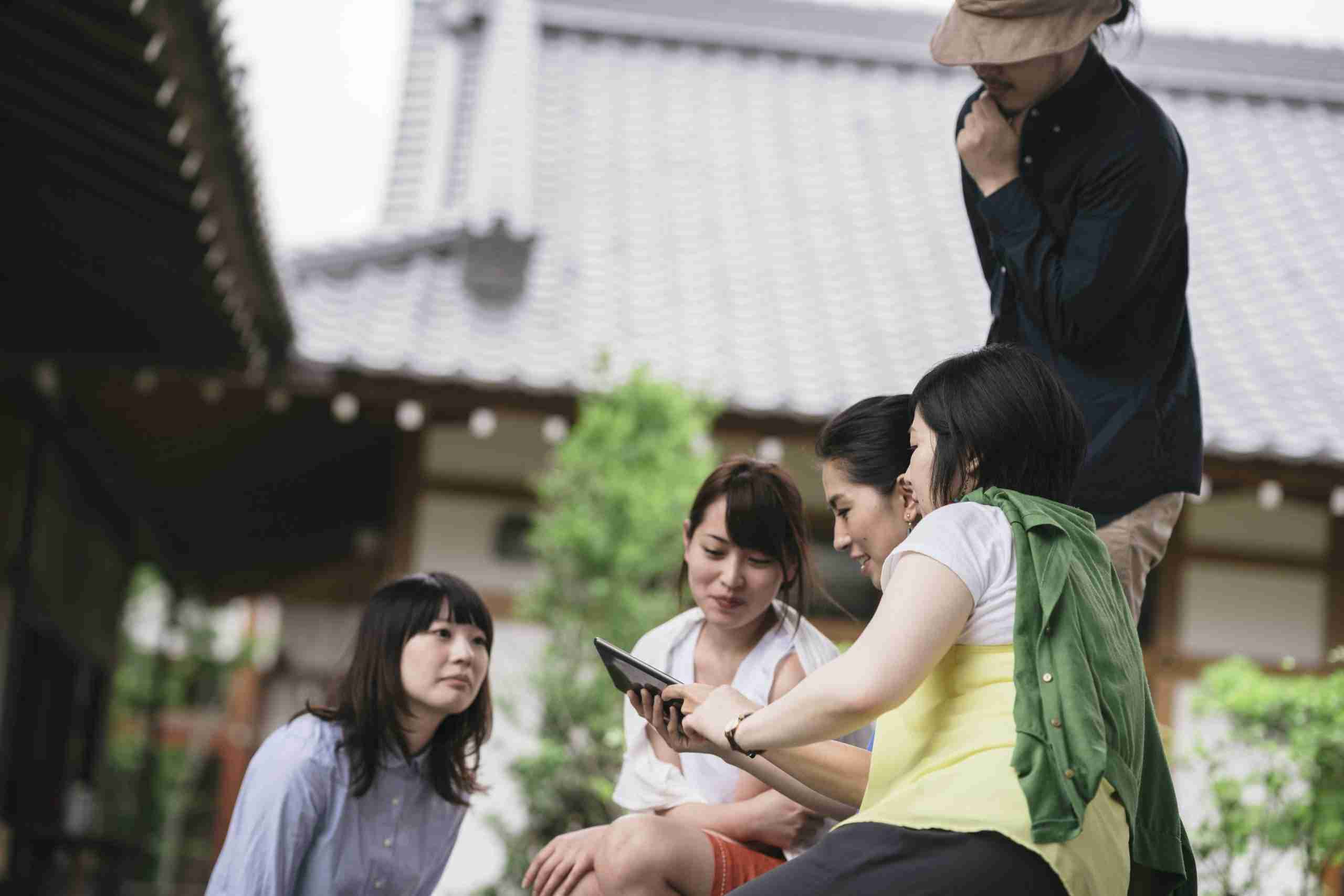 group-of-friends-looking-at-a-tablet-outdoors Grupo de amigos hablando y mirando una tablet